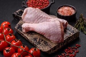 Raw chicken legs with salt, spices, herbs and tomatoes photo