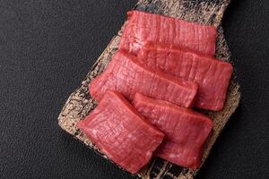 Juicy raw beef cut into slices with salt and spices photo