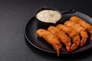 Hot crispy shrimp breaded with salt and spices with white sauce photo