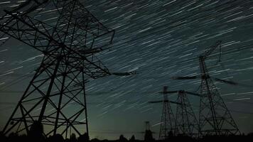 Witness the mesmerizing movement of stars illuminating the night sky above tall power lines in a serene rural landscape. Night time lapse. video