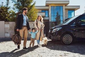 A young family with their son and dog and luggage going by car on vacation for the weekend photo