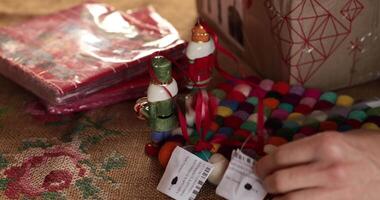 Hands create colorful Christmas decorations using vibrant felt beads and small ornaments on a rustic table. The atmosphere is warm, featuring a cozy holiday ambiance with festive touches. video