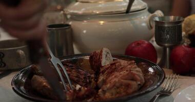 POV hands serve and cut stuffed turkey roll using knife and two prong fork on Thanksgiving dinner table with vintage crockery. Traditional Thanksgiving turkey roulade roasted on grill. Serving dinner video