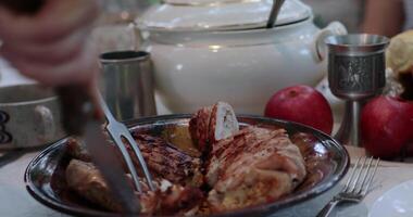 POV hands serve and cut stuffed turkey roll using knife and two prong fork on Thanksgiving dinner table with vintage crockery. Traditional Thanksgiving turkey roulade roasted on grill. Serving dinner video