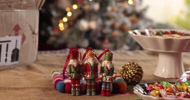 Festive table setting featuring charming nutcracker figurines surrounded by vibrant candies. Warm ambiance and twinkling lights create a delightful holiday atmosphere with blurred Christmas lights video