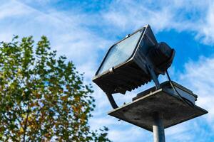 A floodlight mounted on a pole against a blue sky in autumn photo