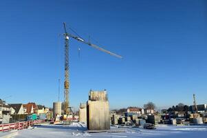 Snow-covered construction site with concrete structures and a construction crane. photo