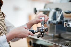 Barista tamping espresso grounds, showcasing precision and professionalism in a cafe setting. photo
