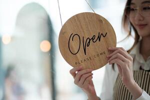 Shopkeeper flipping an open sign at the storefront, signaling the start of the business day. photo