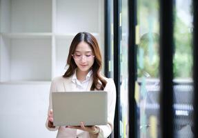 Businesswoman using a laptop and reviewing data with sticky notes in the background. photo
