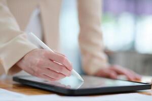 Close-up of hand signing electronic documents on a tablet with a digital pen for online workflows photo