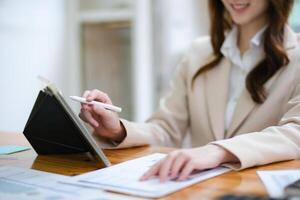 Businesswoman analyzing charts and using a tablet for data review photo