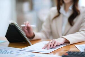 Businesswoman analyzing charts and using a tablet for data review photo