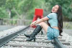 A woman in boots sitting on a railroad track photo