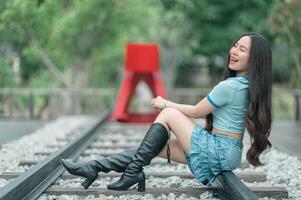 A woman in boots sitting on a railroad track photo