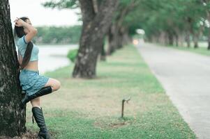 A woman leaning against a tree photo