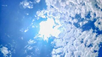 The sun shines through the clouds in a blue sky photo