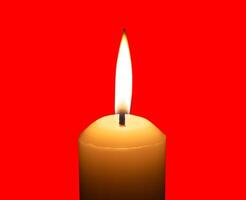 A single burning candle flame or light glowing on a big white candle isolated on red background with clipping path photo
