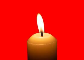 A single burning candle flame or light glowing on a big white candle isolated on red background with clipping path photo