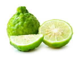 Front view of fresh green bergamot fruits or kaffir lime with half and quarter or slices but no green leaf in stack isolated on white background with clipping path photo