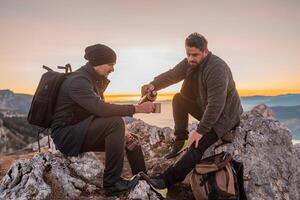 Two happy friends tourists drinking a cup of coffee or tea during the hiking on the mountain adventure travel. photo