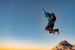 A happy man jumping on top of a mountain concept of adventure travel extreme sport hiking. photo