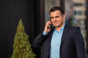 A happy young business man talking on his phone mobile outside near the office building. photo