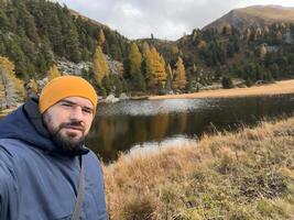 A happy man traveler taking selfie while walking in the autumn forest. photo