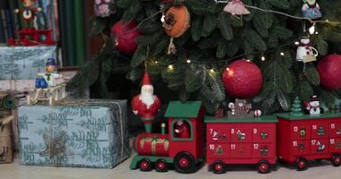 The Christmas tree is beautifully adorned with colorful ornaments and playful decorations. Presents are arranged beneath the tree, creating a warm holiday atmosphere filled with joy. video