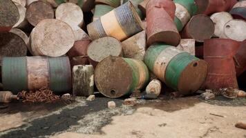 Rusty barrels cluttered on a shoreline during daylight near a coastal area video