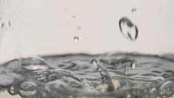 Slow motion of water droplets creating ripples on a surface during a sunny afternoon video