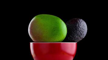 mango, avocado and orange rotate in the red plate on a black background video
