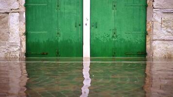 Wide dark green painted gates reflect in high flood water video