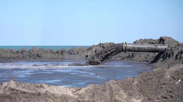 Mud flows in slow motion out of a tube on the beach video