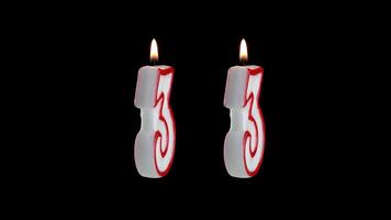 Candle in the shape of the number thirty three on a black background video