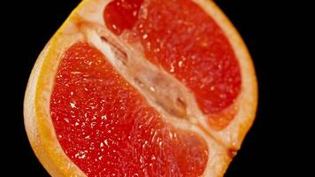 Red grapefruit cut in two on a black background video