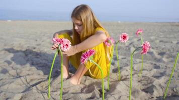 Girl sitting with flowers planted in the sand of the beach video