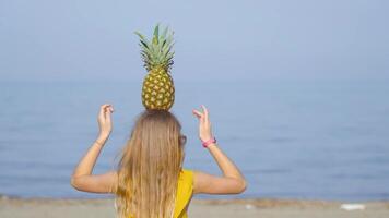 Girl on the beach balances a pineapple on the head video