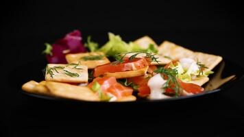 small snack canapes with crackers and lightly salted red fish Salmon, isolated on black background video