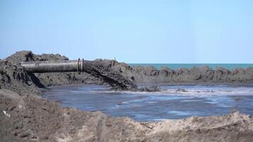 Mud comes out in slow motion from a pipe at the beach video