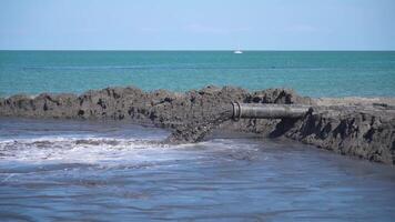 Mud flows in slow motion out of a tube on the beach video