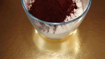Bowl with flour and cocoa powder stands on golden table video