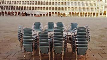 Stacked chairs and tables of closed cafe on empty square video
