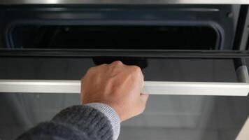 A person is using their hand to open a modern oven, engaging in culinary activities at home video