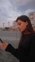 A young woman relaxes on the beach at sunset, enjoying peace and capturing the moment video
