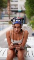 A Young Woman is Enjoying a Leisurely Day, Relaxing by the Poolside, Using Her Phone video