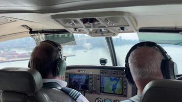Vancouver Canada 20.09.2024 Pilots approaching coastal city skyline in airplane cockpit. Two pilots navigate an airplane as they approach a coastal city skyline, visible through the cockpit windows. video
