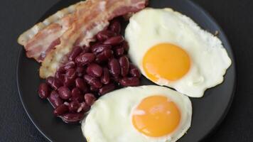 English breakfast with fried eggs, bacon, beans, tomatoes, spices and herbs. A hearty and nutritious start of the day video