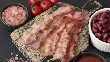 Bacon sliced, grilled with salt and spices on a dark concrete background video