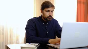 Young man freelancer student using laptop working from home in internet, focused millennial guy typing on computer surfing web looking at screen enjoying distant job video